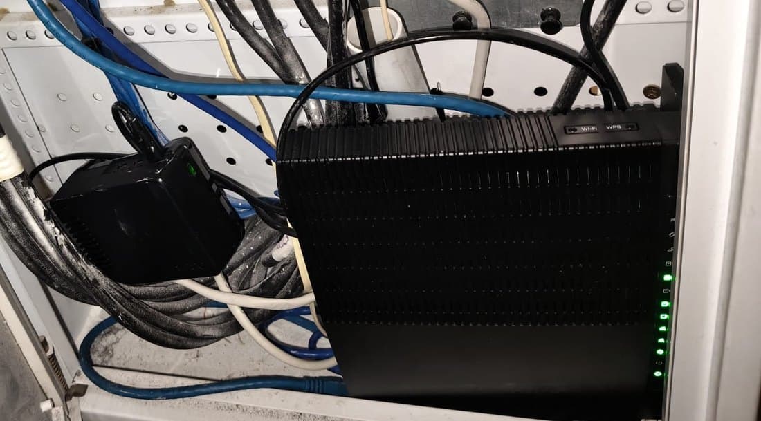 Bilal's Shield Vault installed in his home comms cabinet, status light on, beside a modem several times its size.