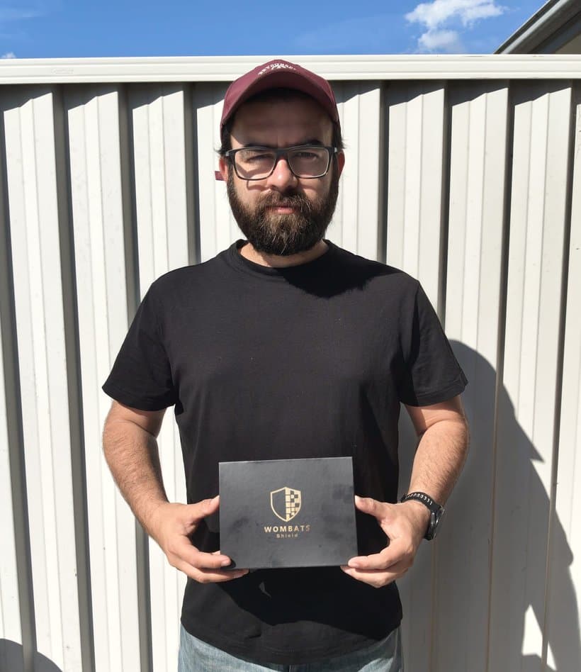 Bilal outside his house holding the WOMBATS Shield box.